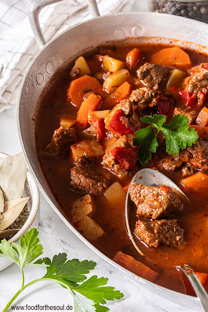 Gulaschsuppe mit Kartoffeln und Paprika im großen Topf garniert mit Petersilie