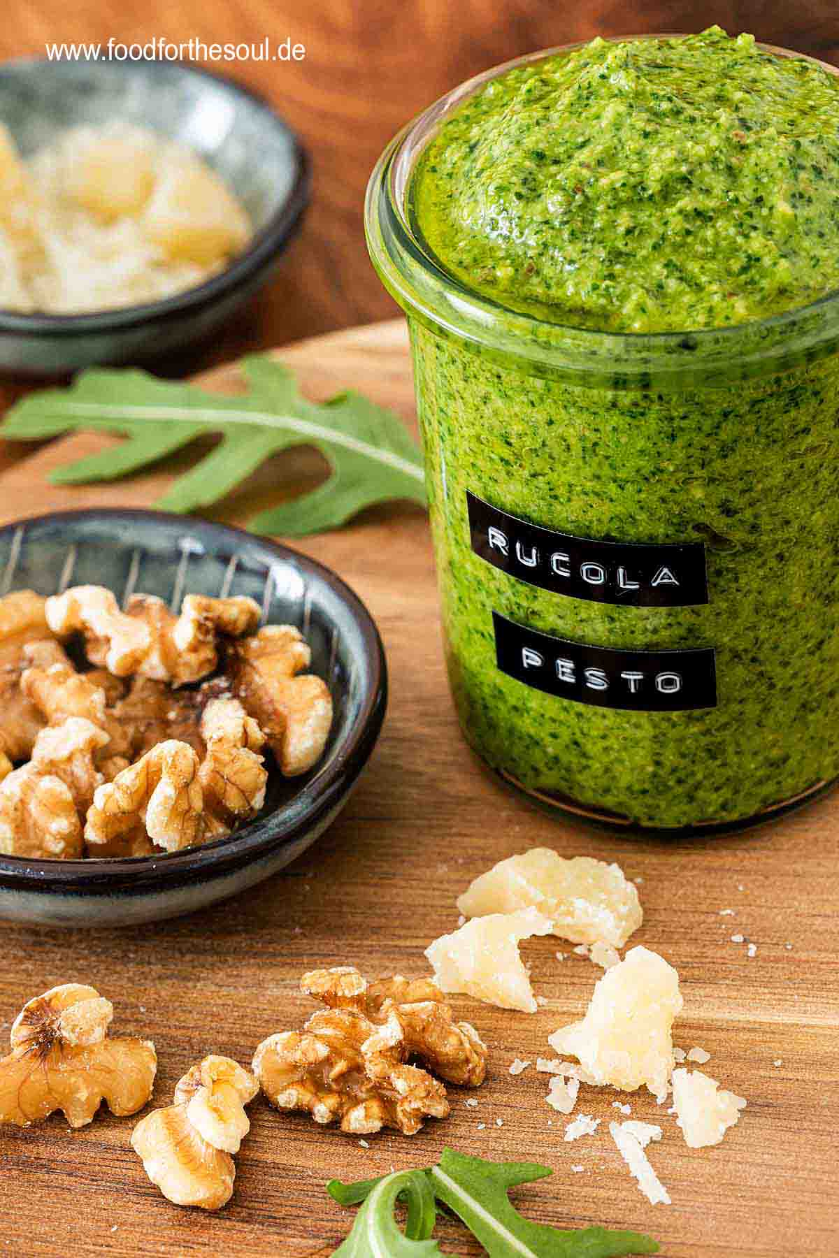Selbstgemachtes Rucola Pesto in einem beschrifteten Glas umgeben von Zutaten