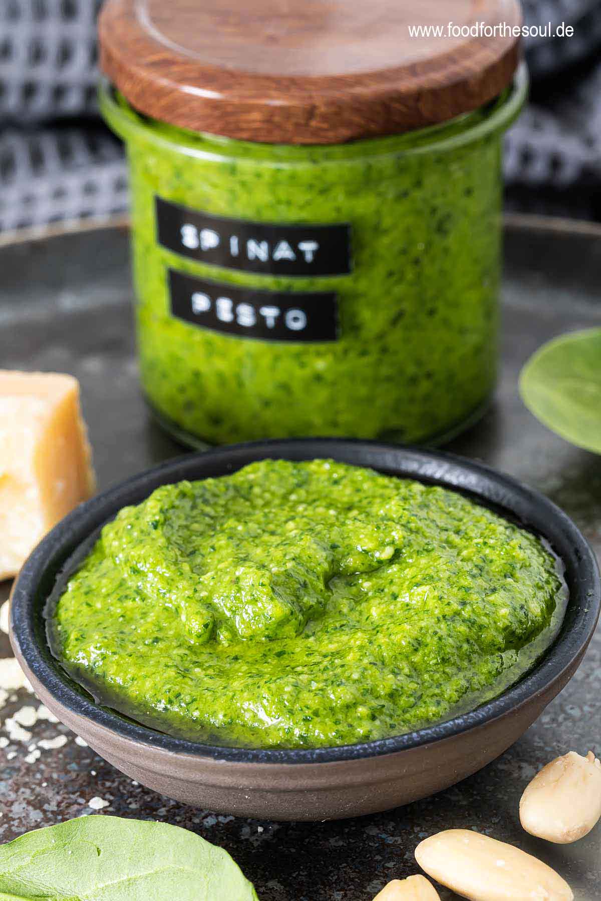 Frisch zubereitetes Spinat Pesto in einer Schale, dahinter ein beschriftetes Glas mit Spinatpesto