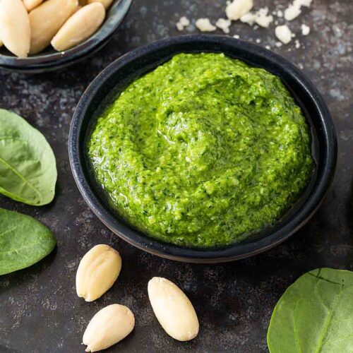 Frisch zubereitetes Spinat Pesto in einer Schale, daneben Spinatpesto im Glas mit Deckel