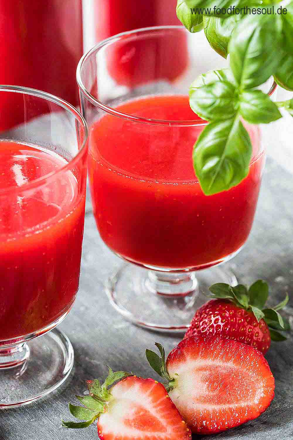 Zwei Glaser mit selbstgemachtem Erdbeer Likör, daneben liegen Erdbeeren