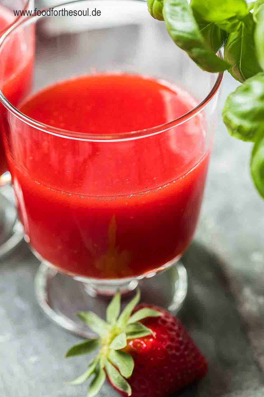 Selbstgemachter Erdbeer Limes in einem Glas, daneben liegt eine Erdbeere