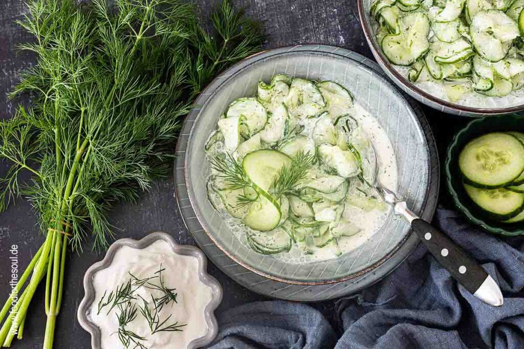 Gurkensalat mit saurer Sahne und Dill serviert in einer Schale, daneben ein Bund Dill