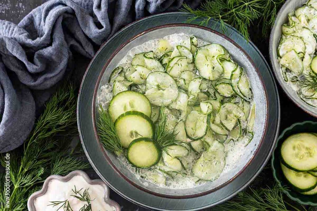 Gurkensalat mit saurer Sahne und Dill serviert in einer Schale, daneben ein Bund Dill