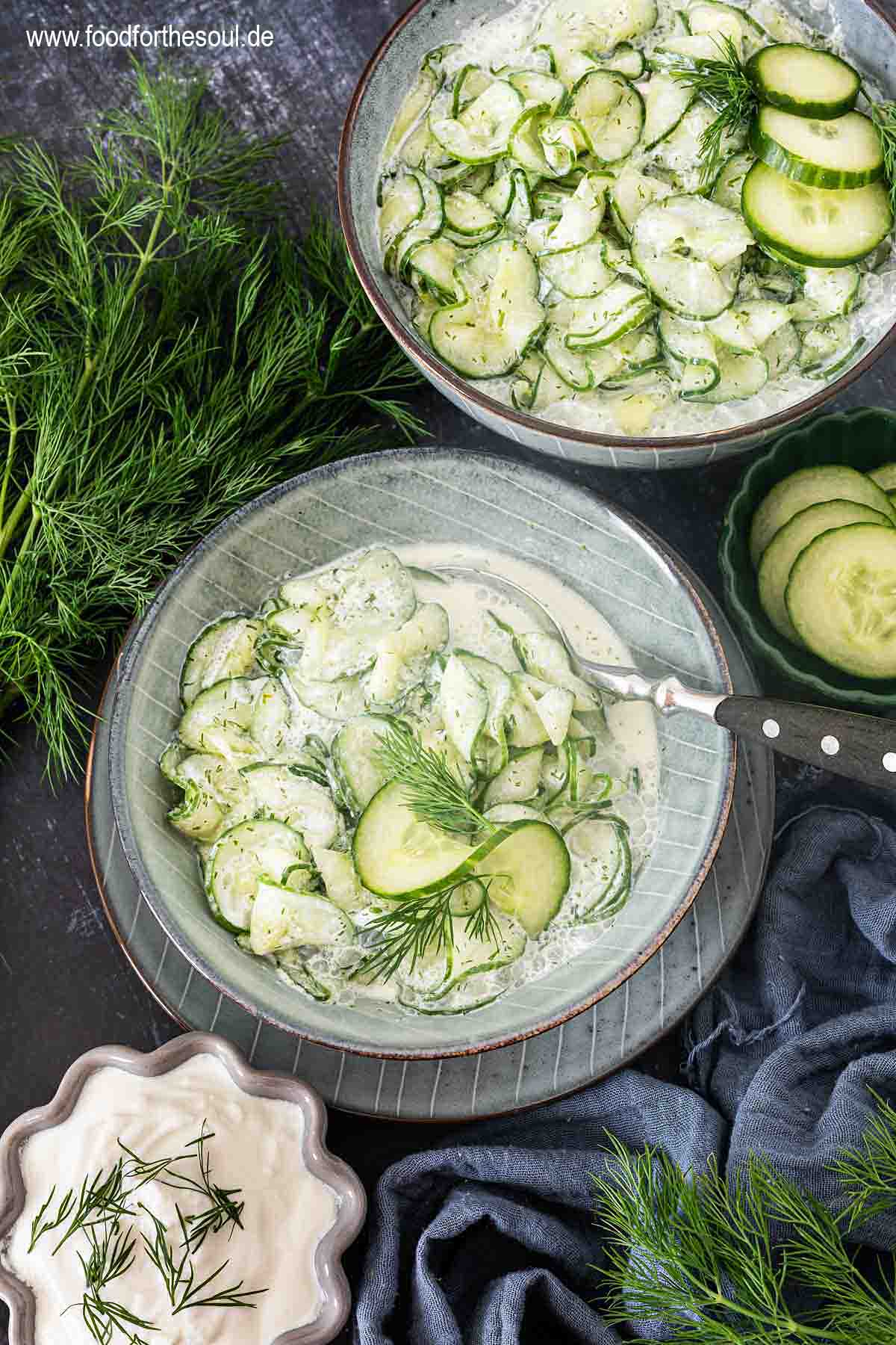 Gurkensalat mit saurer Sahne und Dill serviert in einer Schale, daneben ein Bund Dill