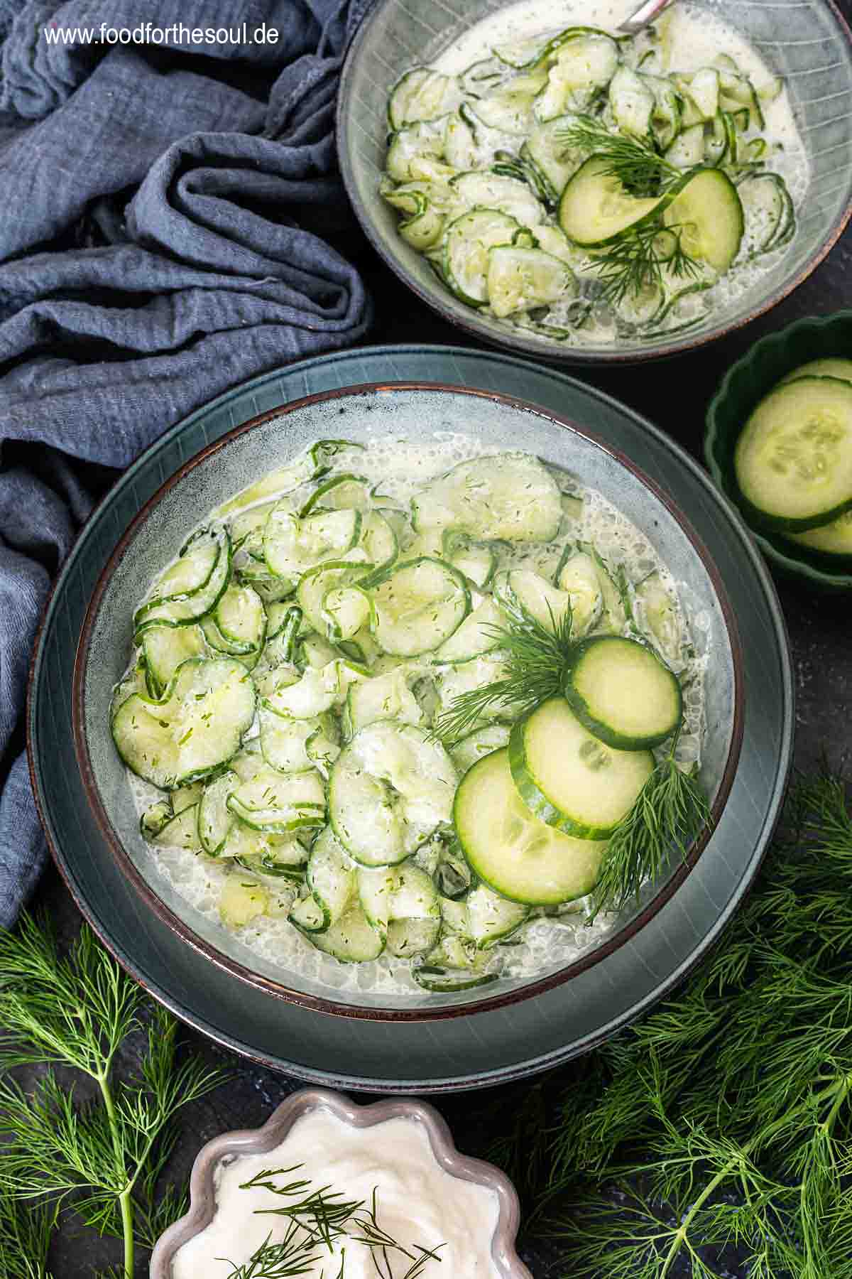 Gurkensalat mit saurer Sahne und Dill serviert in einer Schale, daneben ein Bund Dill