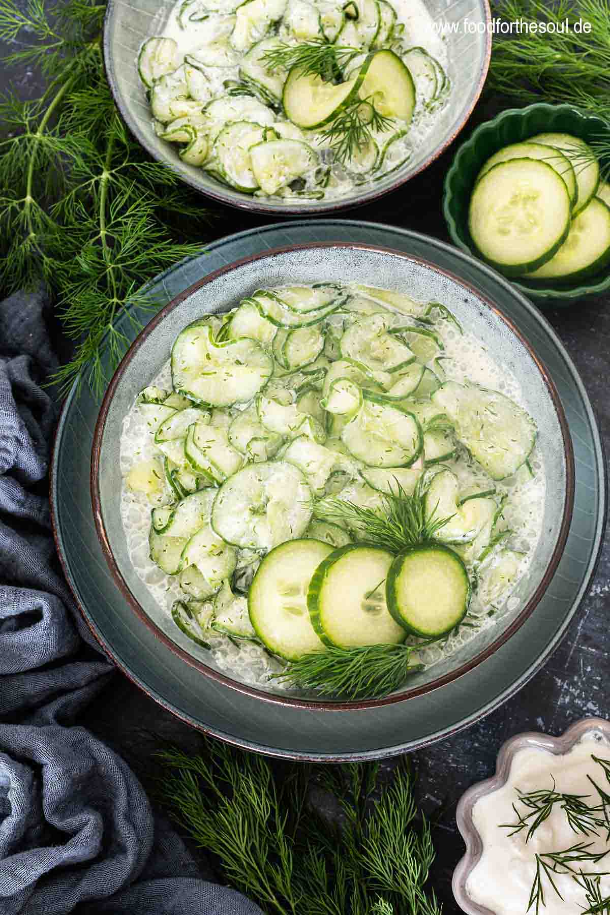Gurkensalat mit saurer Sahne und Dill serviert in einer Schale, daneben ein Bund Dill