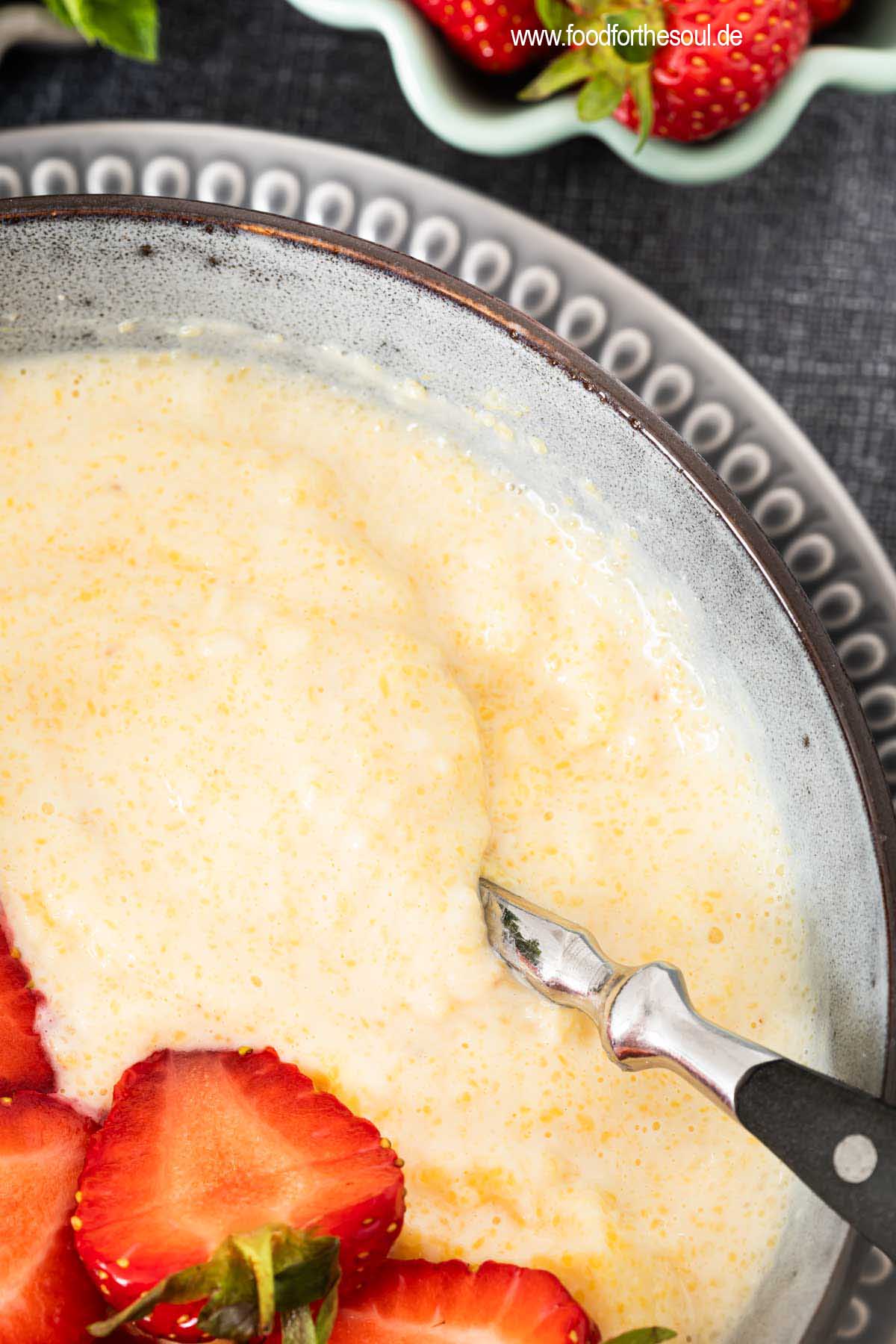 Süße Polenta - Maisbrei auf einem Teller garniert mit Erdbeeren und Minze