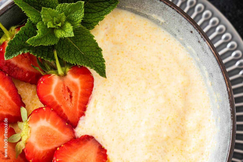 Süße Polenta - Maisbrei auf einem Teller garniert mit Erdbeeren und Minze