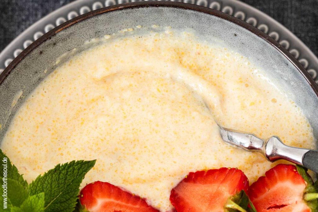 Süße Polenta - Maisbrei auf einem Teller garniert mit Erdbeeren und Minze