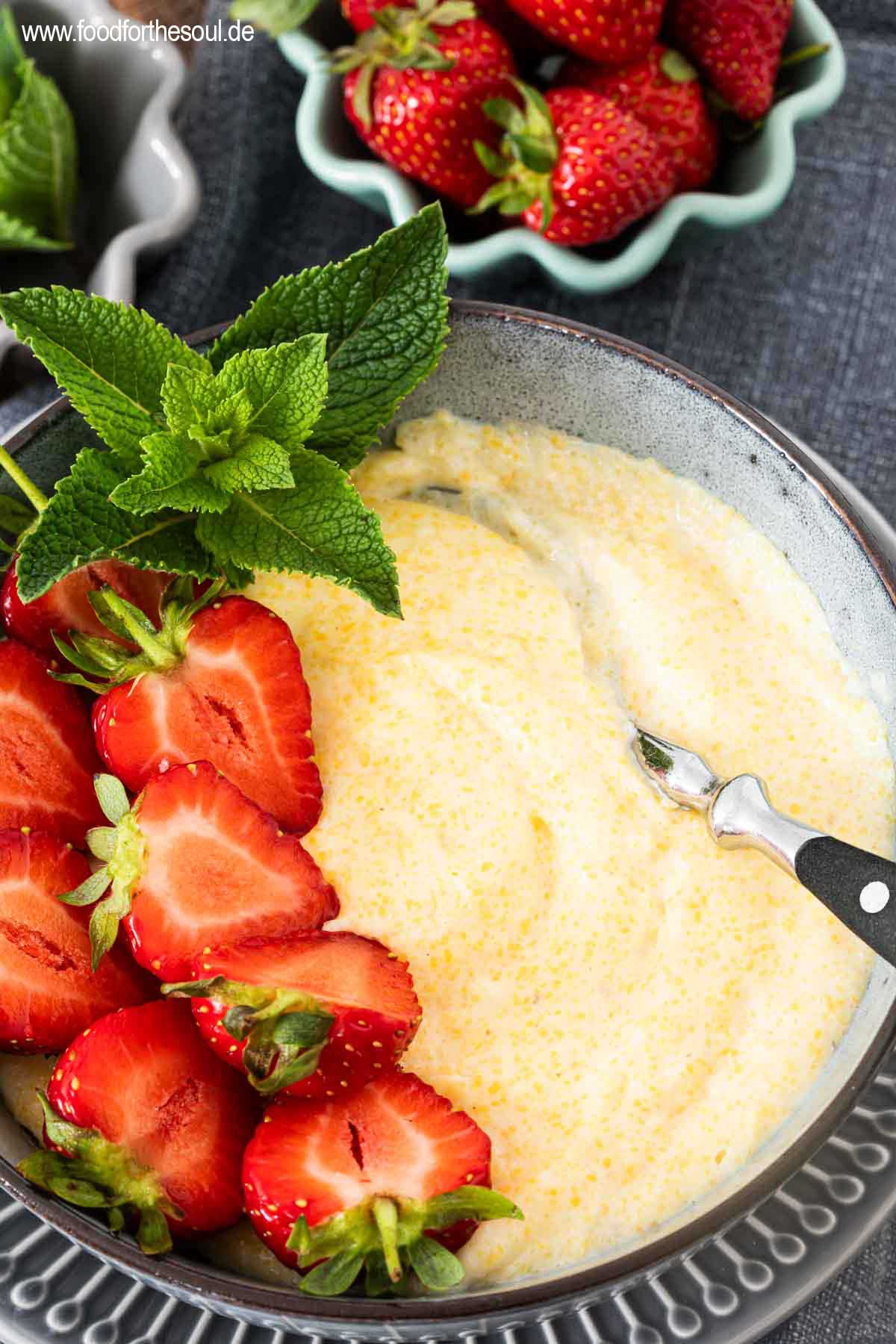 Süße Polenta - Maisbrei auf einem Teller garniert mit Erdbeeren und Minze
