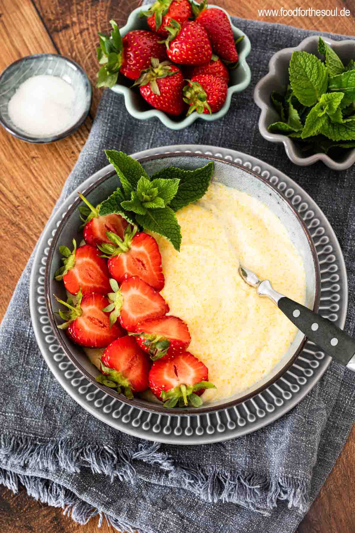 Süße Polenta - Maisbrei auf einem Teller garniert mit Erdbeeren und Minze