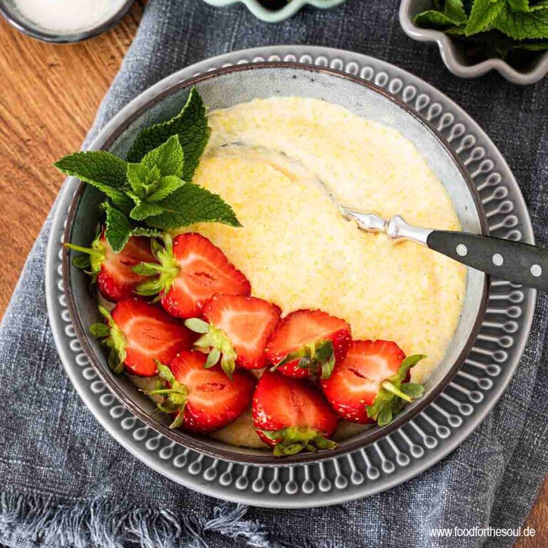 Süße Polenta - Maisbrei auf einem Teller garniert mit Erdbeeren und Minze
