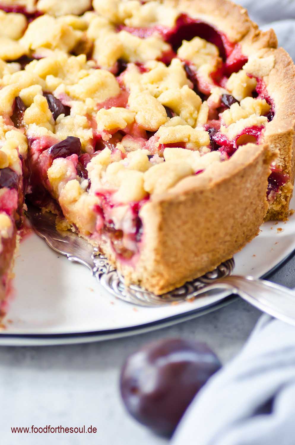 Omas Zwetschgenkuchen mit Streusel auf Mürbeteig auf einem Kuchenteller