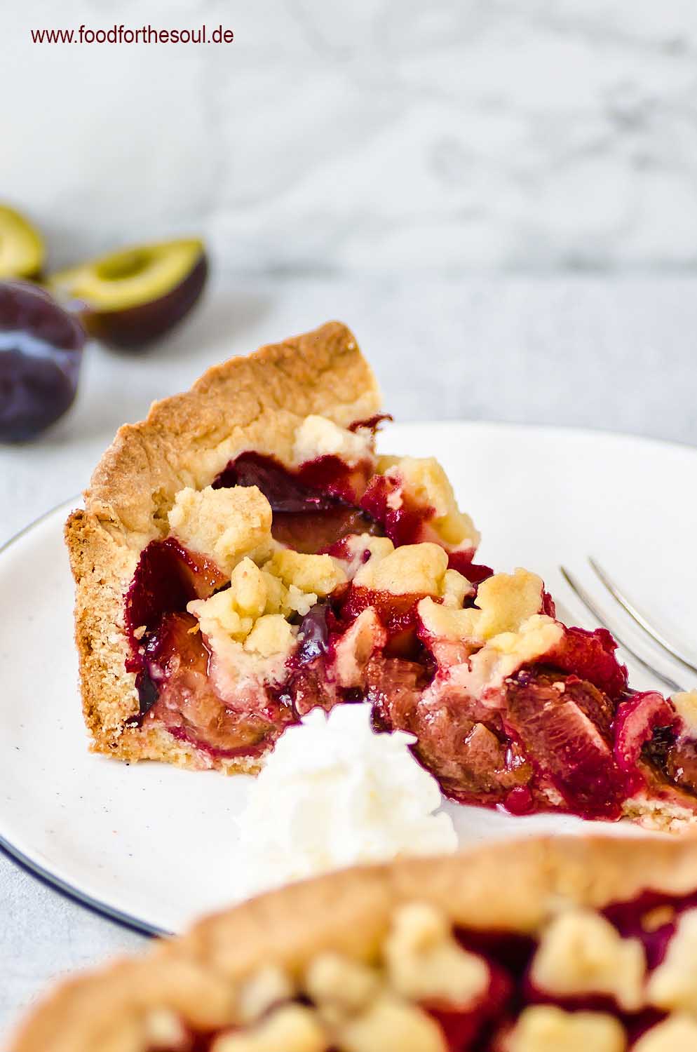 Ein Stück von Omas Zwetschgenkuchen mit Streusel auf Mürbeteig auf einem Kuchenteller