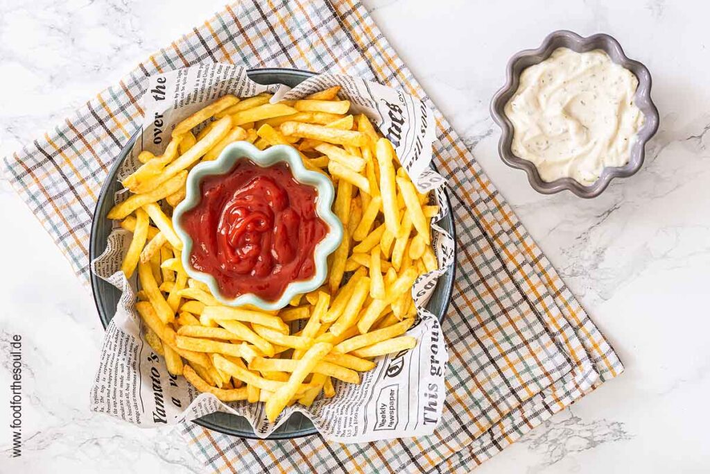 TK Pommes aus dem Airfryer in einer Schale angerichtet mit Ketchup, daneben eine Schale mit Mayonnaise