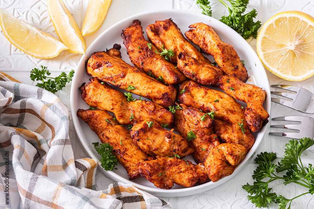 Hähnchenbruststreifen im Airfryer zubereitet und auf einem Teller serviert