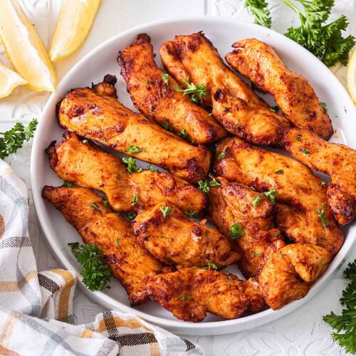 Hähnchenbruststreifen im Airfryer zubereitet und auf einem Teller serviert