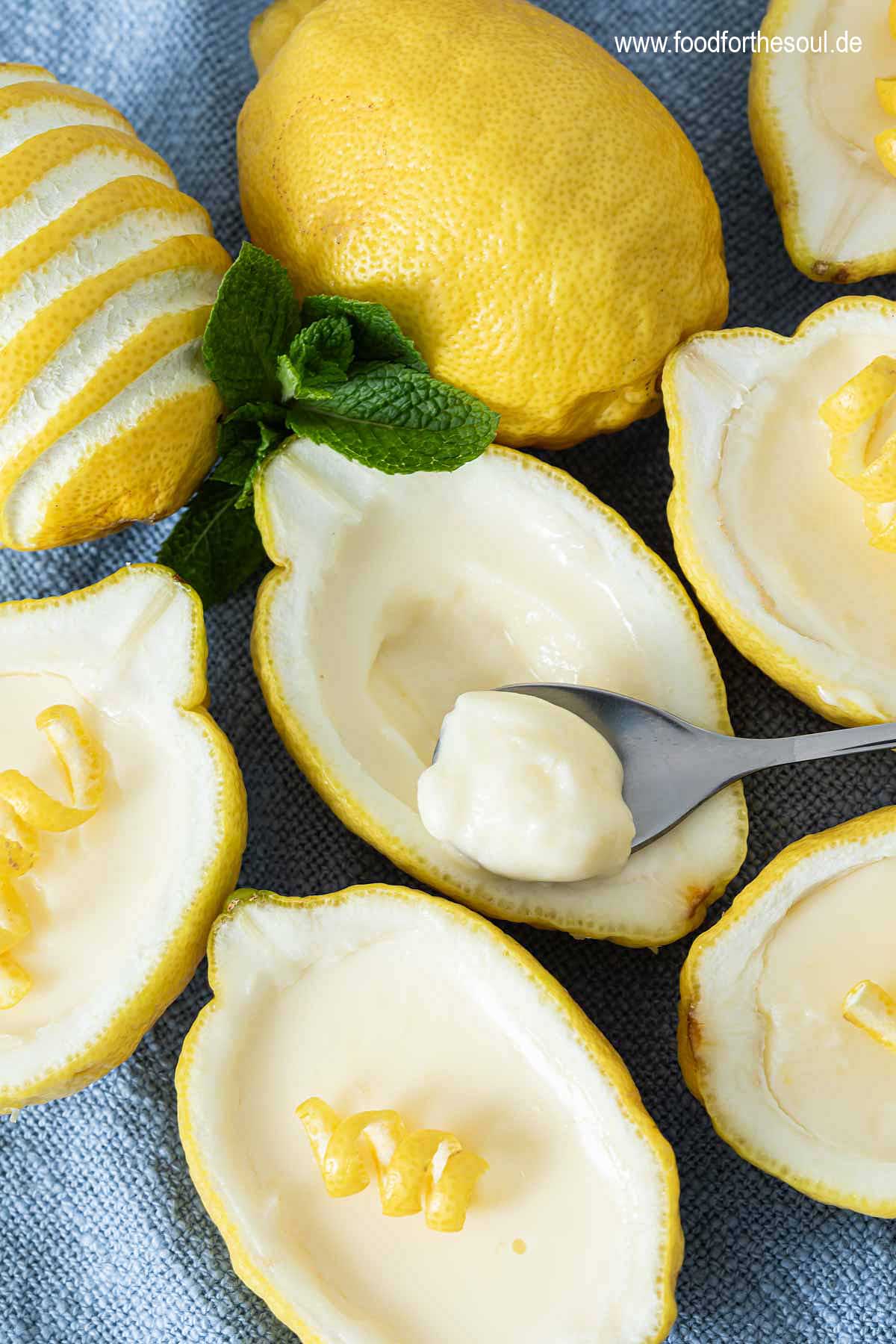 Lemon Posset Dessert in Zitronen gefüllt und garniert mit Minze und Zitronenschale