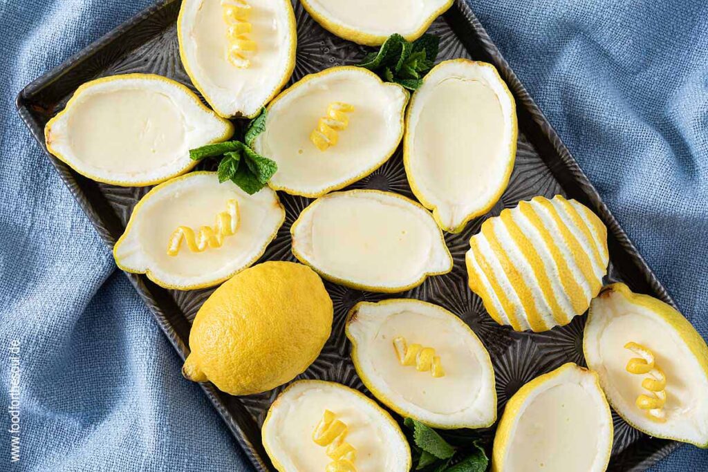 Lemon Posset Dessert in Zitronen gefüllt und garniert mit Minze und Zitronenschale