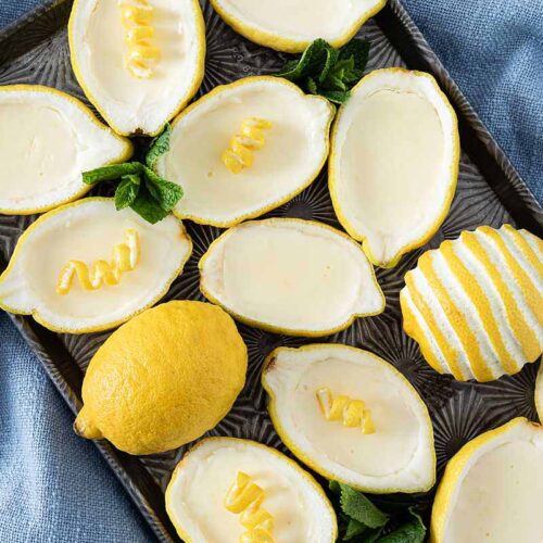 Lemon Posset Dessert in Zitronen gefüllt und garniert mit Minze und Zitronenschale