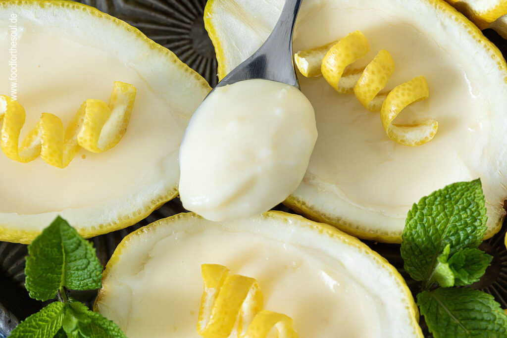 Lemon Posset Dessert in Zitronen gefüllt und garniert mit Minze und Zitronenschale