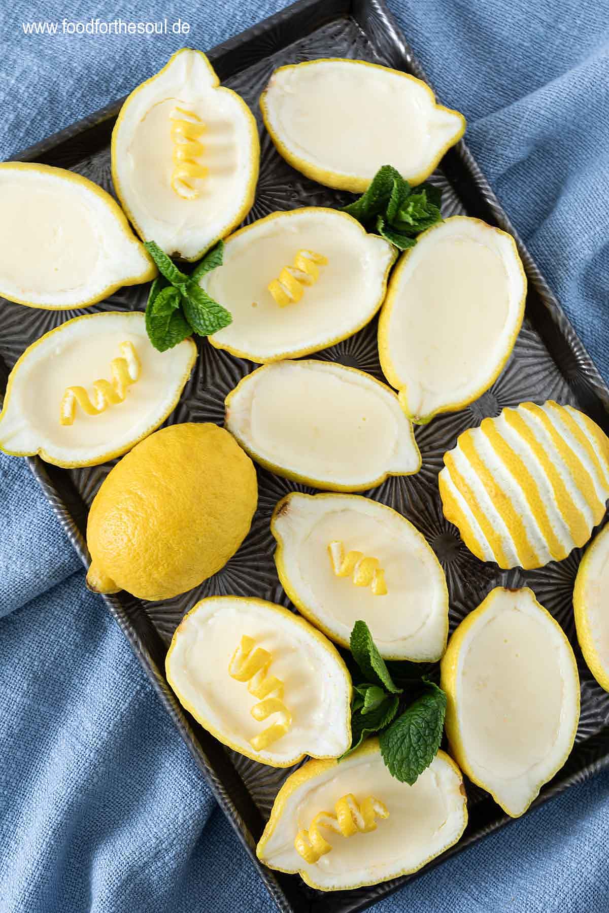 Lemon Posset Dessert in Zitronen gefüllt und garniert mit Minze und Zitronenschale