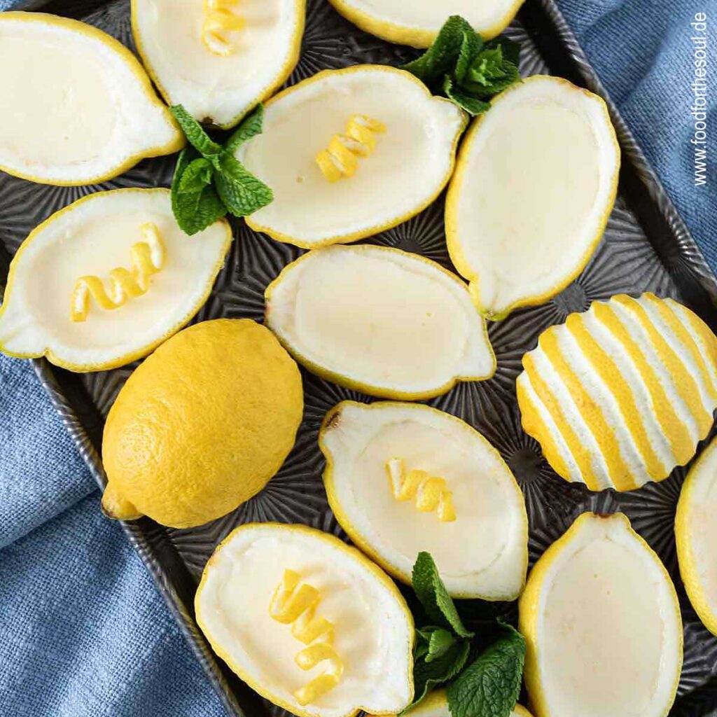 Lemon Posset Dessert in Zitronen gefüllt und garniert mit Minze und Zitronenschale