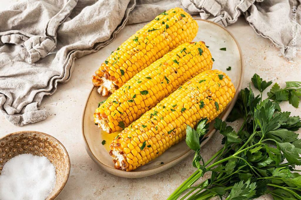 Maiskolben im Airfryer zubereitet und serviert mit Butter und Petersilie