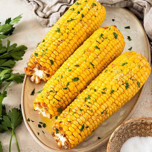 Maiskolben im Airfryer zubereitet und serviert mit Butter und Petersilie