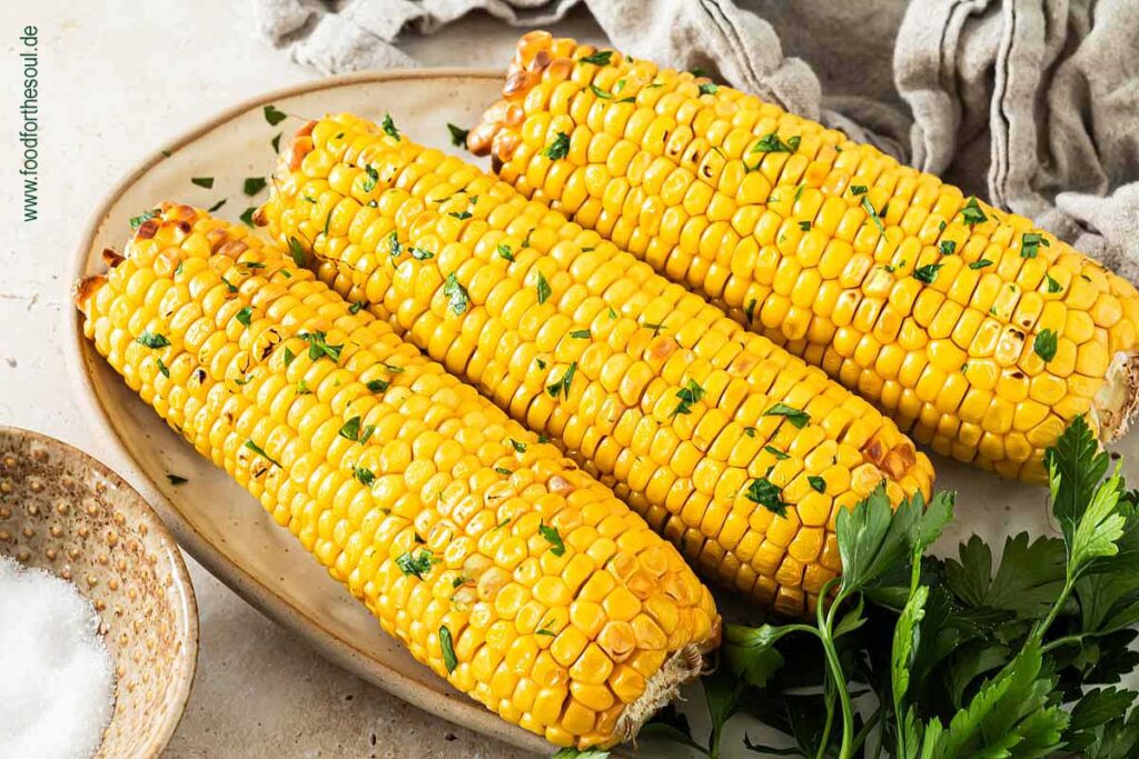 Maiskolben im Airfryer zubereitet und serviert mit Butter und Petersilie