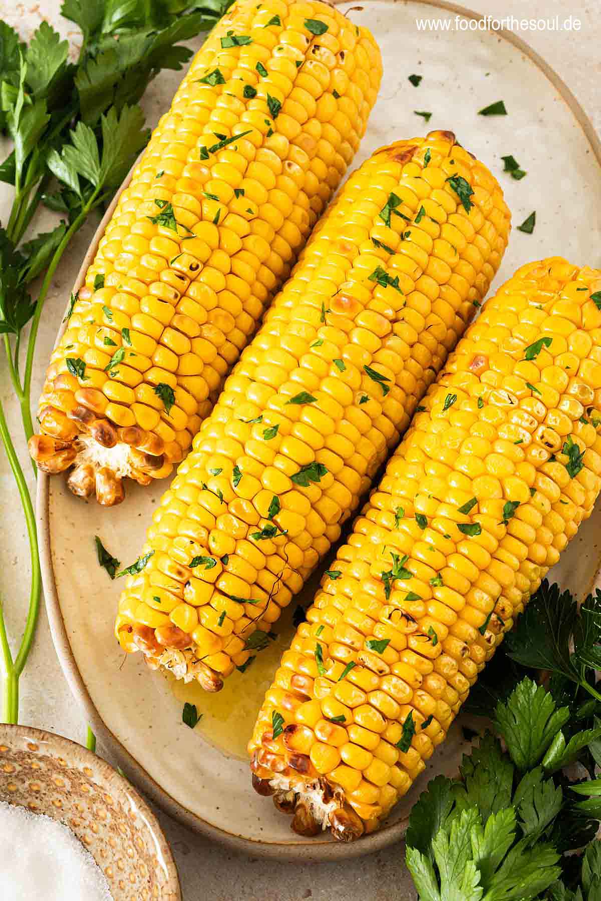 Maiskolben in der Heißluftfritteuse zubereitet und serviert mit Butter und Petersilie