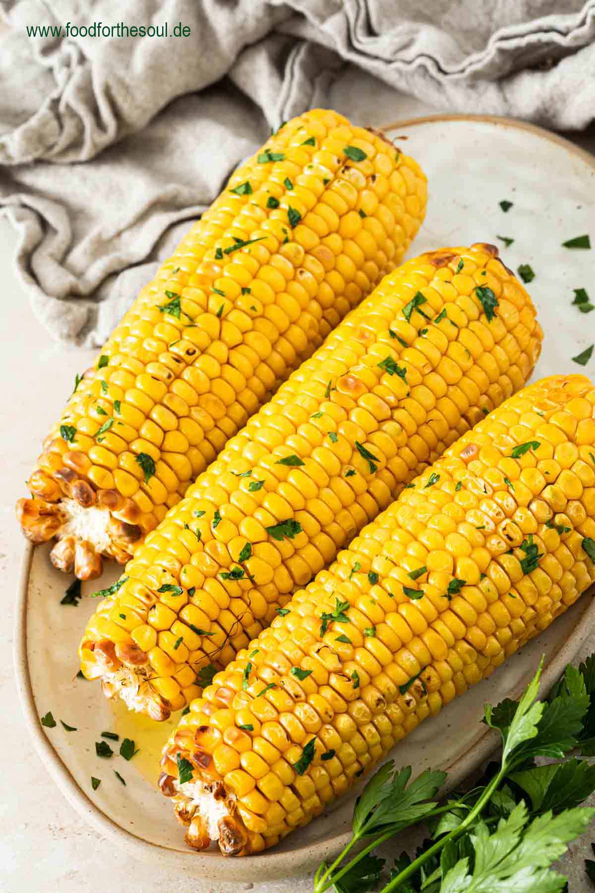Maiskolben im Airfryer zubereitet und serviert mit Butter und Petersilie