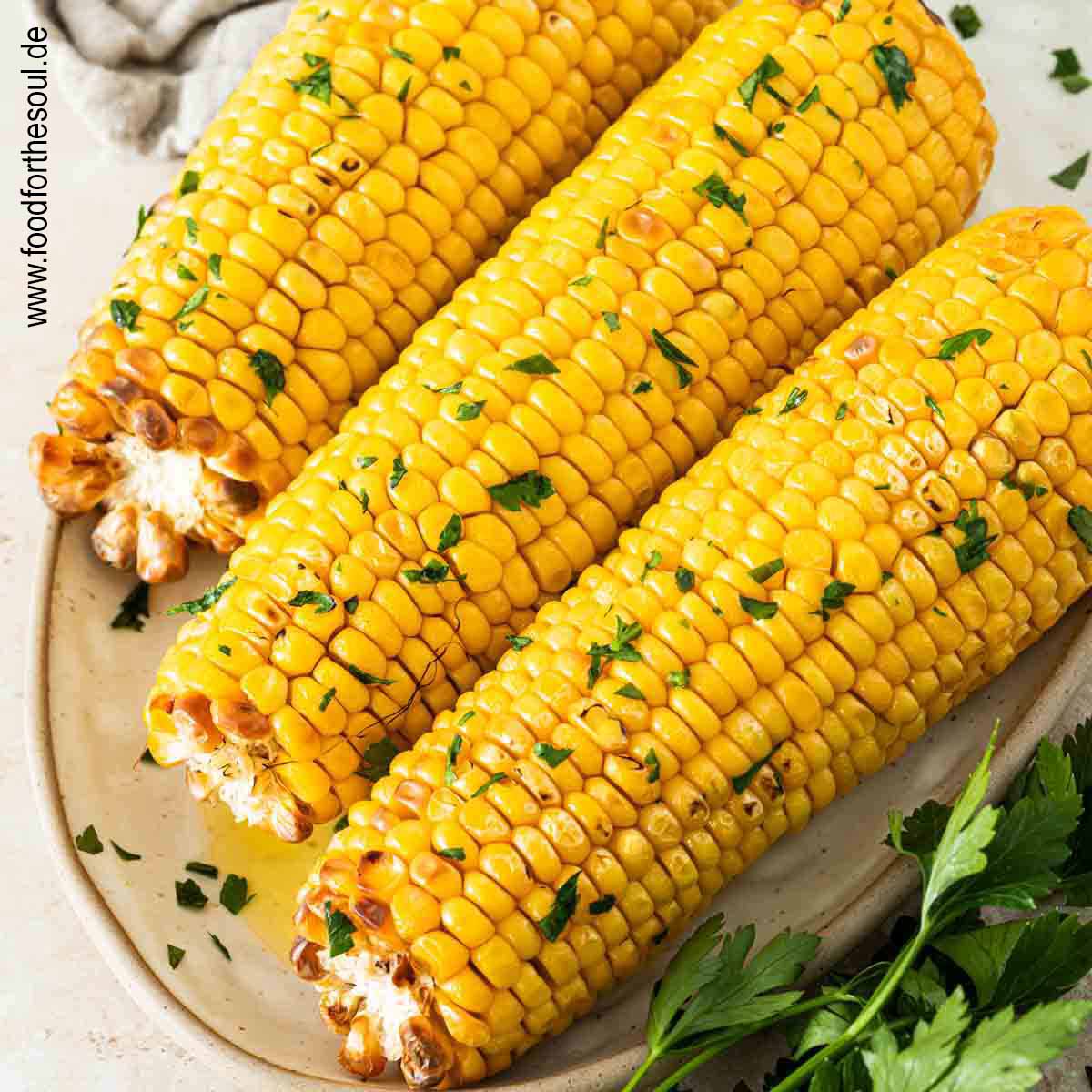 Maiskolben im Airfryer zubereitet und serviert mit Butter und Petersilie