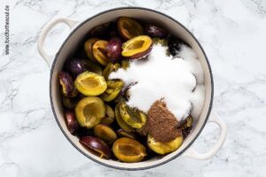 Zucker und Gewürze werden Zwetschgen hinzugefügt für Pflaumenmus im Backofen nach Omas Rezept - Schritt 3
