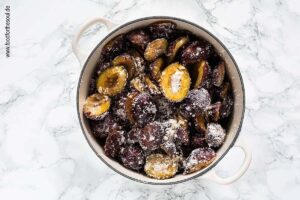 Zwetschgen zuckern in einem Gusseisentopf für Pflaumenmus im Backofen nach Omas Rezept - Schritt 4