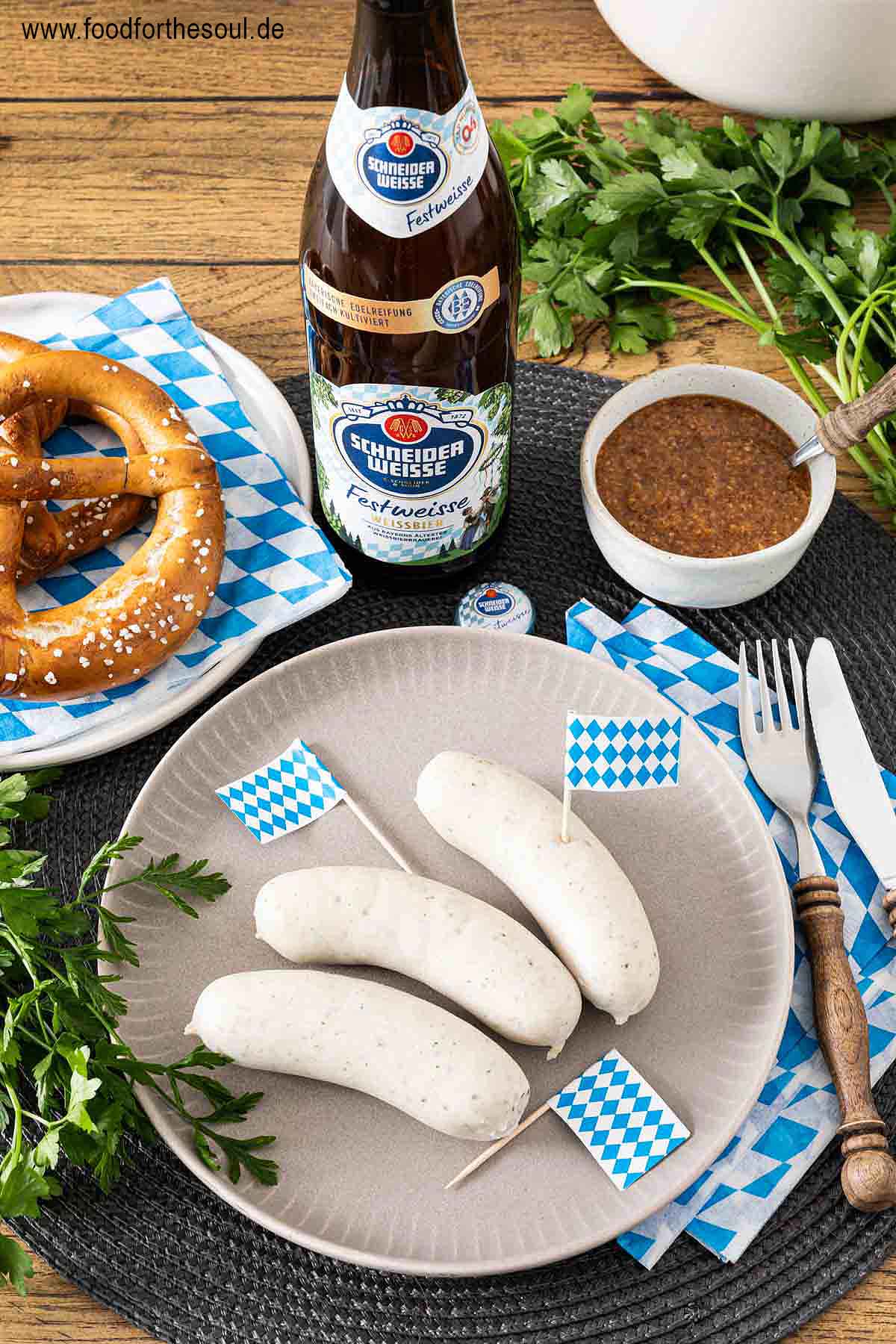 Bayerische Weißwurst serviert mit Brezel, süßem Senf und Hefeweizen