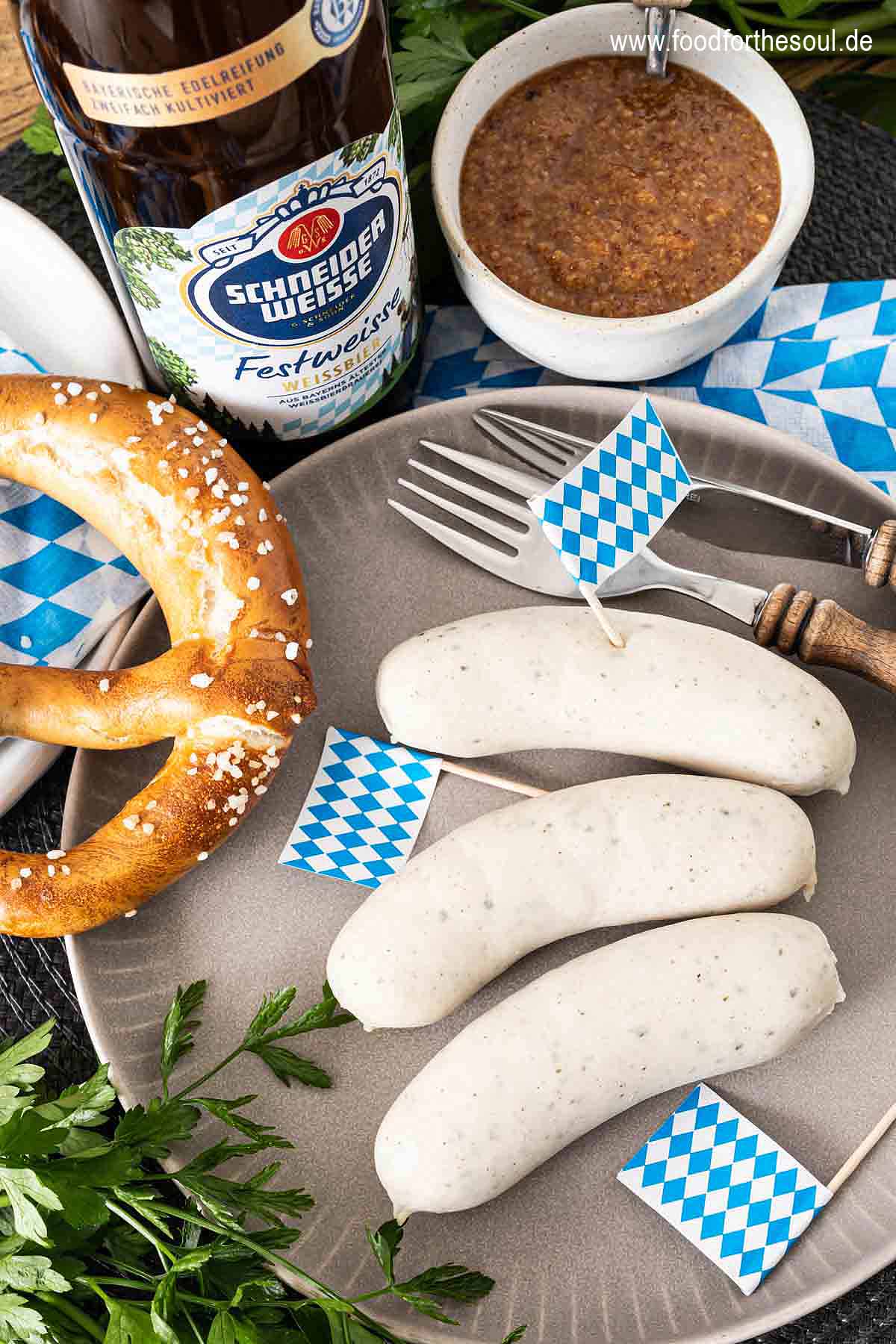Bayerische Weißwurst serviert mit Brezel, süßem Senf und Hefeweizen