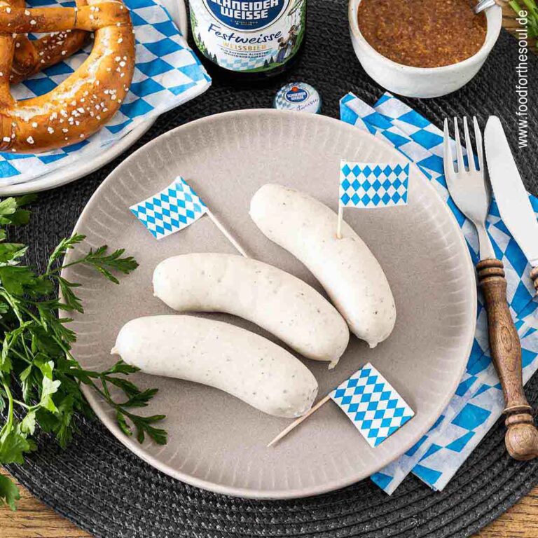 Bayerische Weißwurst serviert mit Brezel, süßem Senf und Hefeweizen