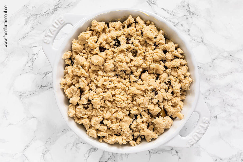 Gezuckerte Zwetschgen und Streusel in Tarteform für Zwetschgen Crumble füllen - Schritt 7