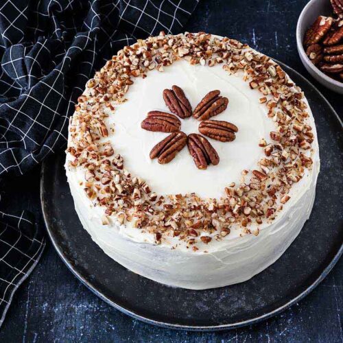 Amerikanischer Kürbiskuchen mit Frischkäse Frosting und Pecan Nüssen serviert auf einem Kuchenteller