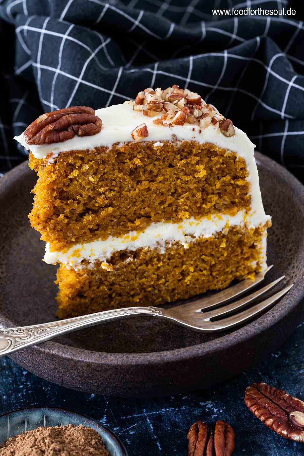 Ein Stück amerikanischer Kürbiskuchen mit Frischkäse Frosting und Pecan Nüssen