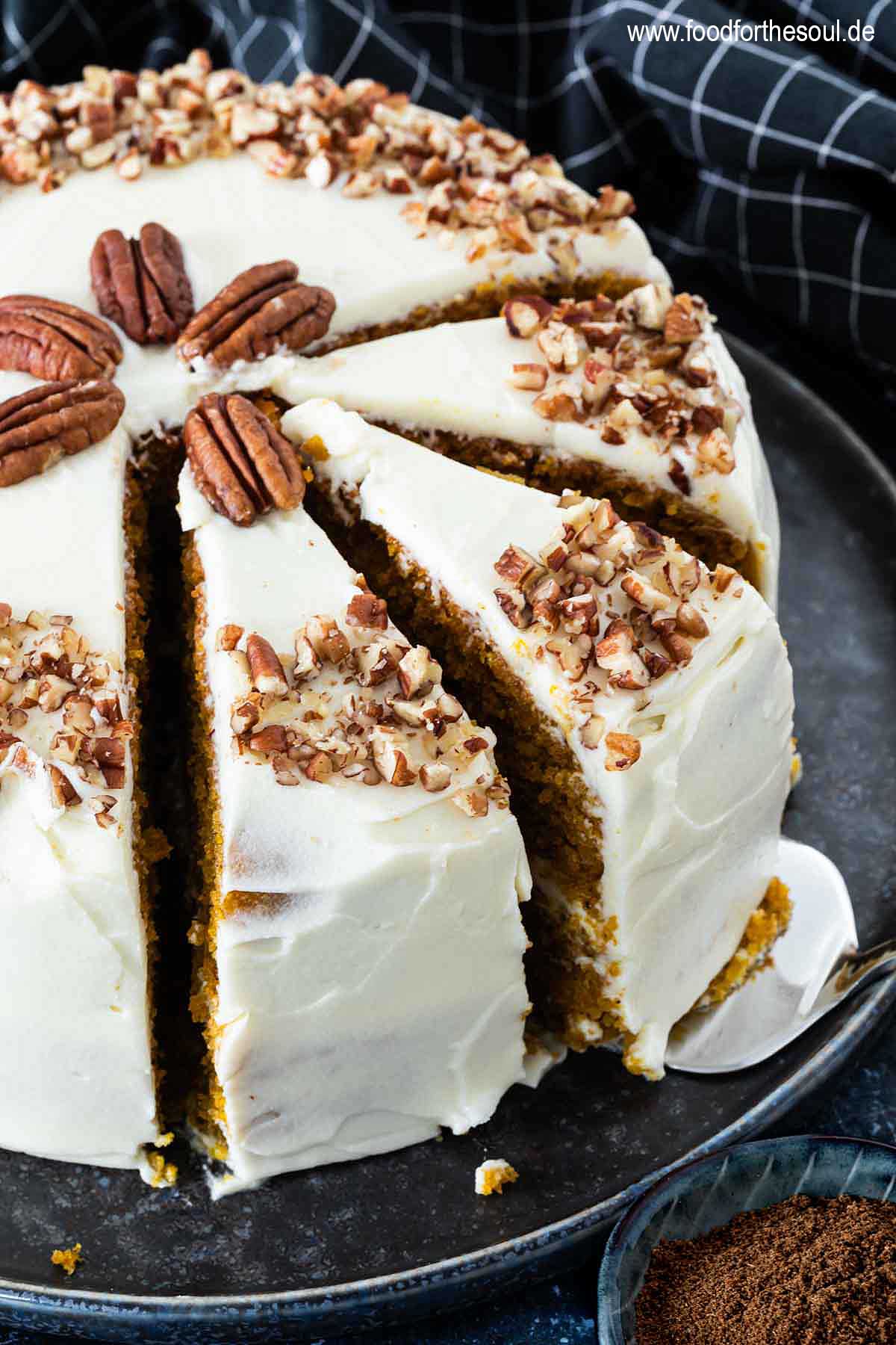 Amerikanischer Kürbiskuchen mit Frischkäse Frosting und Pecan Nüssen serviert auf einem Kuchenteller