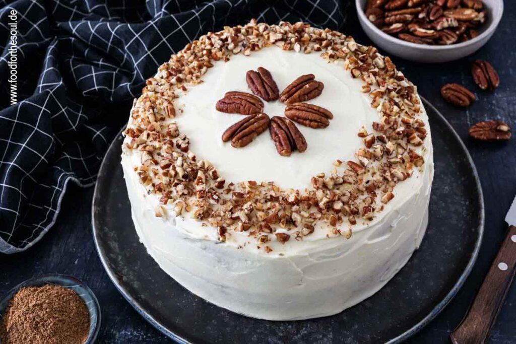 Amerikanischer Kürbiskuchen mit Frischkäse Frosting und Pecan Nüssen serviert auf einem Kuchenteller