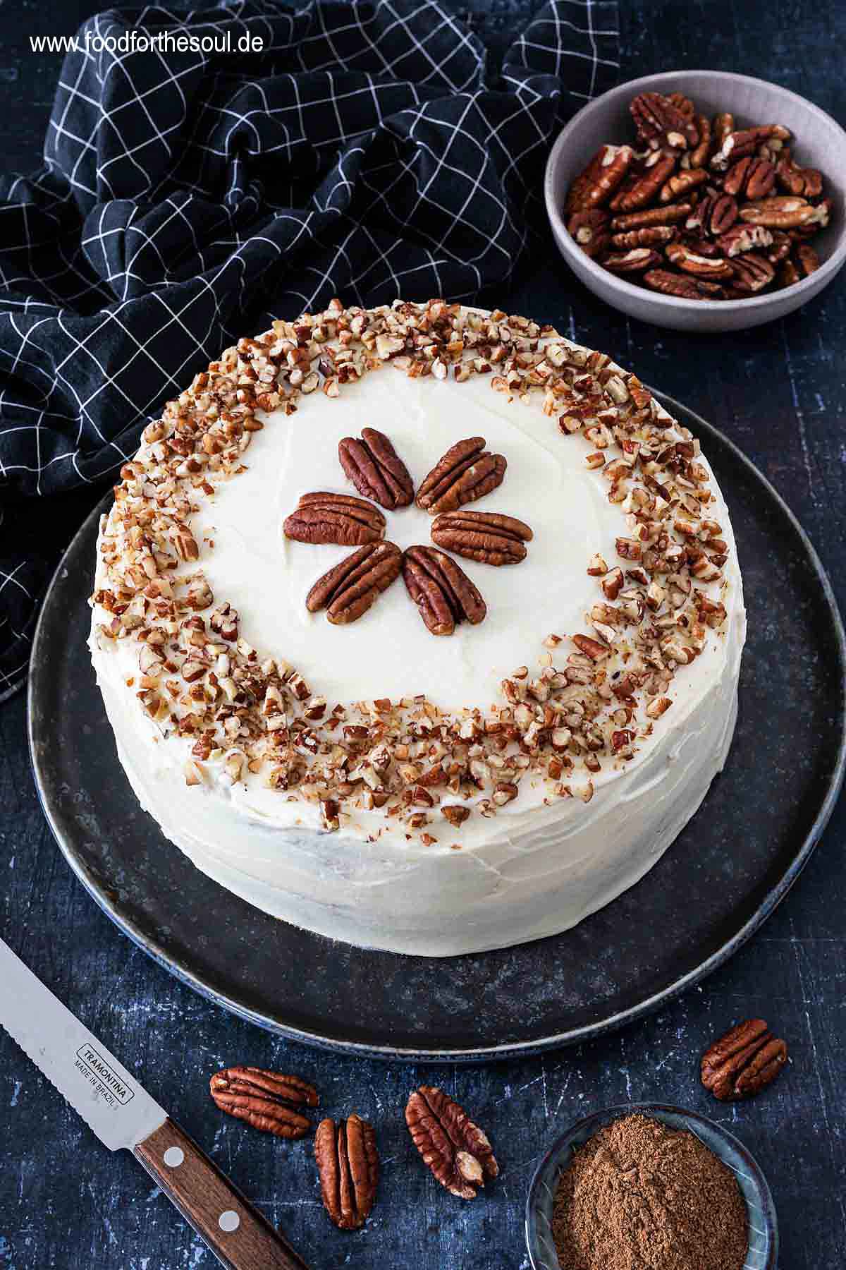 Amerikanischer Kürbiskuchen mit Frischkäse Frosting und Pecan Nüssen serviert auf einem Kuchenteller