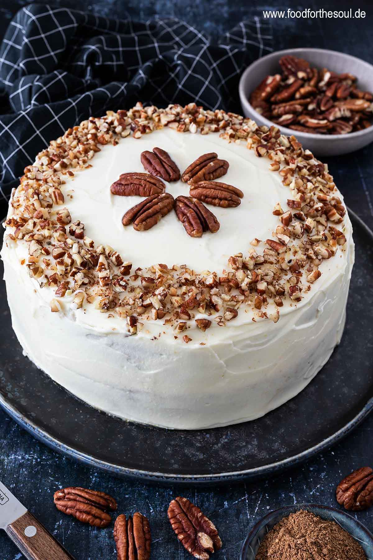 Amerikanischer Kürbiskuchen mit Frischkäse Frosting und Pecan Nüssen serviert auf einem Kuchenteller