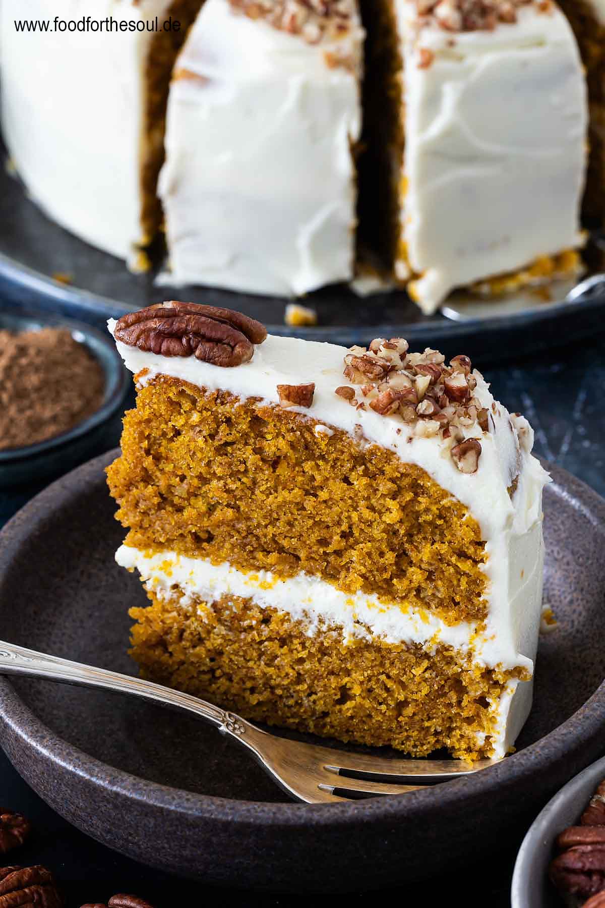 Amerikanischer Kürbiskuchen mit Frischkäse Frosting und Pecan Nüssen serviert auf einem Kuchenteller