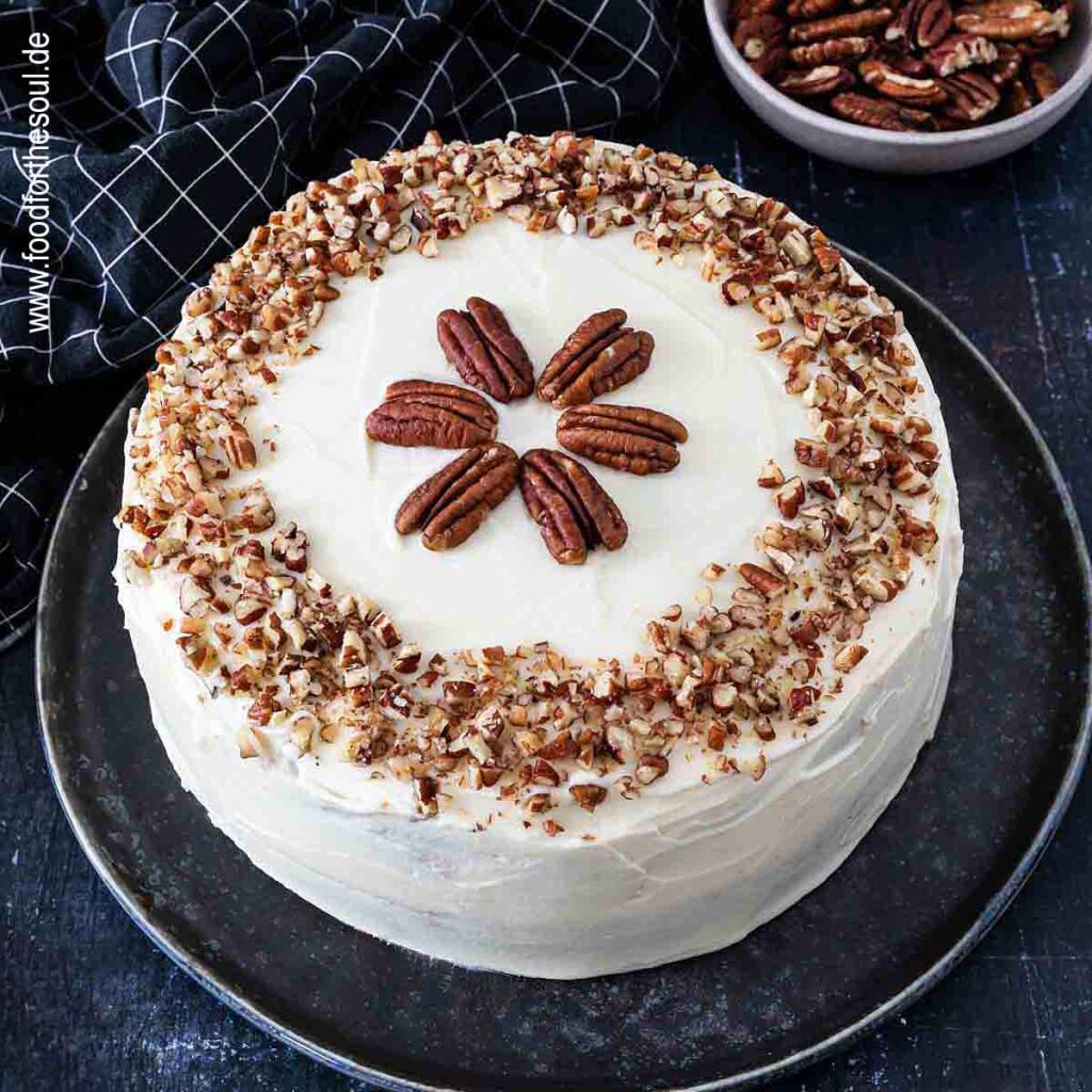 Amerikanischer Kürbiskuchen mit Frischkäse Frosting und Pecan Nüssen serviert auf einem Kuchenteller