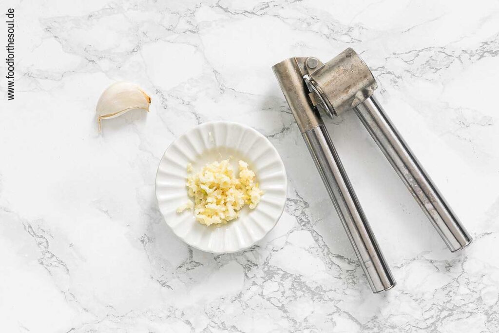 Knoblauch durch eine Knoblauchpresse drücken - Schritt 2