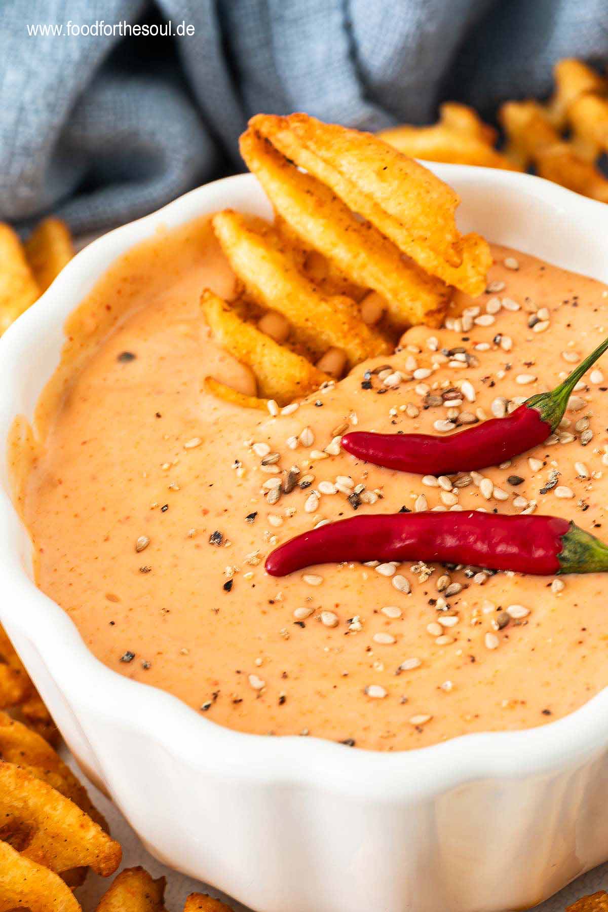 Sriracha Mayonnaise in einer Schale, dekoriert mit Chilis und Sesam